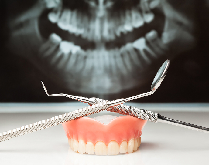 Dentures displayed with dental tools, illustrating restorative dentistry services at Linrose Dental for repairing and replacing missing teeth.