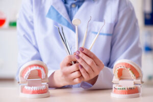 Dental professional holding dental tools in front of dental models, illustrating the services offered at Linrose Dental in Saratoga Springs.